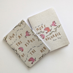 May include: Two small, brown, paper notebooks with a bird and floral design. The text on the notebooks reads "Look at the birds of...heavenly Father feeds them the air" and "Are you not more valuable than they?"