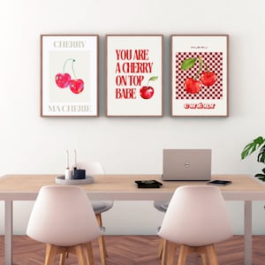 Puede incluir: Tres impresiones enmarcadas con un tema de cereza. La primera impresión dice "CHERRY MA CHERIE" y presenta una ilustración de acuarela de dos cerezas rojas. La segunda impresión dice "YOU ARE A CHERRY ON TOP BABE" y presenta una ilustración de acuarela de una sola cereza roja. La tercera impresión dice "mon CHÉRI" y presenta una ilustración de acuarela de dos cerezas rojas sobre un fondo a cuadros rojo y blanco.
