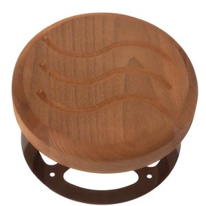 Peut inclure: Un tabouret rond en bois avec une finition marron. Le siège du tabouret présente trois lignes ondulées sculptées. La base est en métal marron foncé avec un design circulaire. Le tabouret est conçu pour s'asseoir.