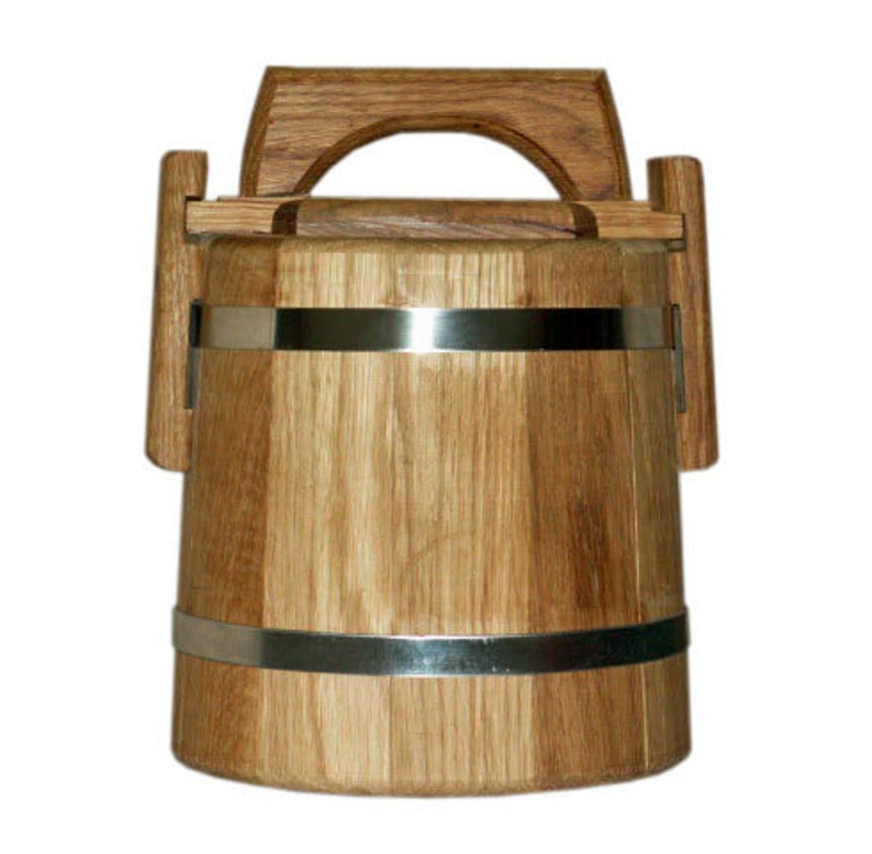 May include: A wooden bucket with a metal band and a handle. The bucket is made of light brown wood and has a natural finish.