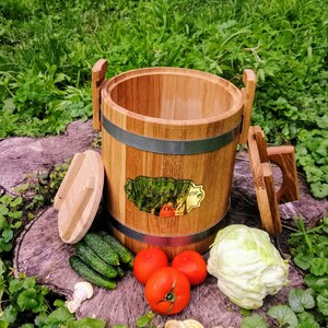 May include: A wooden barrel with a metal band and a brass plaque that reads "Make Your Own Pickle". The barrel is sitting on a tree stump with cucumbers, tomatoes, and a head of cabbage around it.