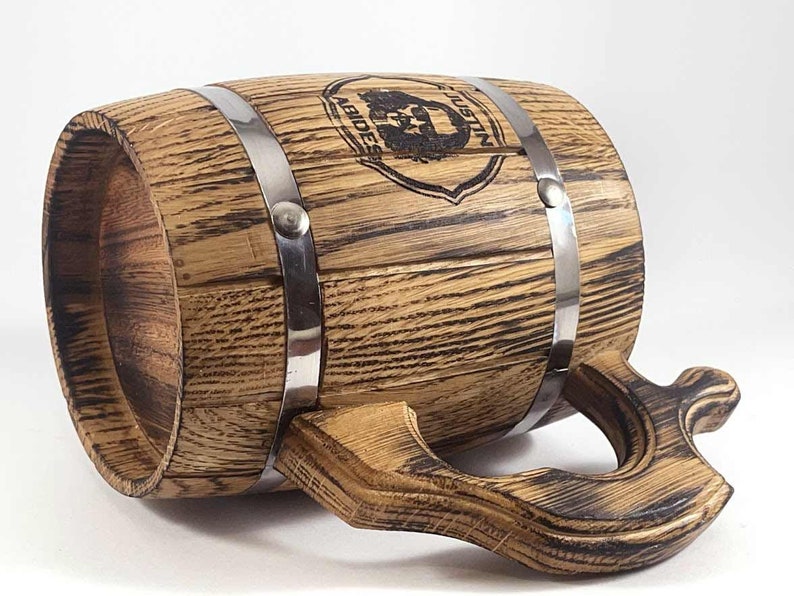 May include: A wooden beer stein with a metal band and a handle. The stein is decorated with a black and white image of a bearded man with the text "Justin Abides".