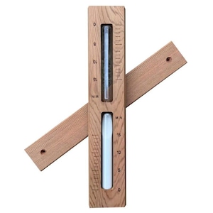 May include: A wooden hourglass timer with two glass tubes, one filled with green sand and the other with white sand. The timer is set for 15 minutes and has a wooden base and a wooden arm.