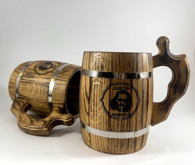 May include: Two wooden beer mugs with metal bands. The mug on the right has the text "Justin Abides" and a cartoon image of a man with sunglasses.