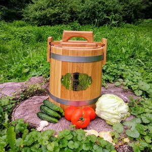May include: A wooden barrel with a metal band and a brass plaque that reads "Homemade Pickles". The barrel is sitting on a tree stump with cucumbers, tomatoes, and a head of cabbage around it.
