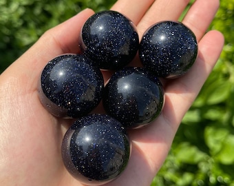 May include: Five smooth, dark blue, polished, gemstone spheres with a sparkly, speckled texture.