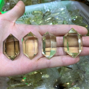 May include: Four clear, faceted, double-terminated quartz crystal points in various sizes. The crystals are a light yellow color and have a translucent appearance.