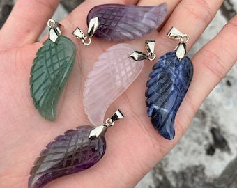 Puede incluir: Cinco colgantes de ala de ángel de piedra preciosa con un aro de plata. Las alas están talladas en amatista, aventurina verde, cuarzo rosa, sodalita azul y amatista.