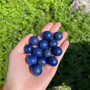 Puede incluir: Una colección de 14 esferas de lapislázuli pulidas, redondas y lisas de diferentes tamaños. Las esferas son de color azul intenso con motas de pirita dorada.