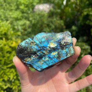 以下が含まれることがあります： 虹色の青、緑、金色の光沢を持つ、大きなラフカットのラブラドライト結晶。結晶は自然で、未加工の外観をしています。