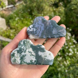 May include: Two green and white agate cloud shaped stones. The stones are smooth and polished.