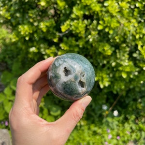 Puede incluir: Esfera de &aacute;gata verde y blanca con un agujero natural en el centro. La esfera es lisa y pulida.