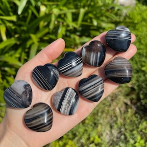 Puede incluir: Ocho piedras de ágata en forma de corazón con rayas blancas y negras. Las piedras están pulidas y tienen un acabado liso y brillante.
