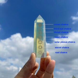 Peut inclure: Une pointe de cristal transparente avec sept symboles de chakra dorés gravés dessus. Les symboles représentent les chakras couronne, troisième œil, gorge, cœur, plexus solaire, sacré et racine.