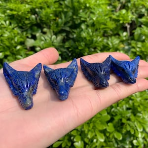 May include: Four blue lapis lazuli wolf head carvings. The carvings are detailed and have a smooth, polished finish.