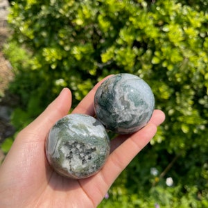Puede incluir: Dos esferas de &aacute;gata verde y blanca con un acabado druzy. Las esferas son lisas y pulidas, y tienen un aspecto natural y org&aacute;nico.