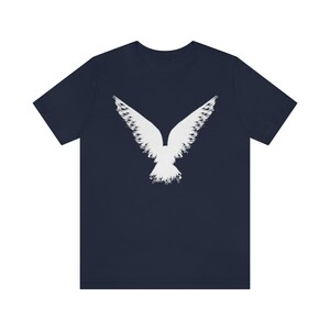 May include: A navy blue t-shirt with a white stylized image of a bird with its wings spread.