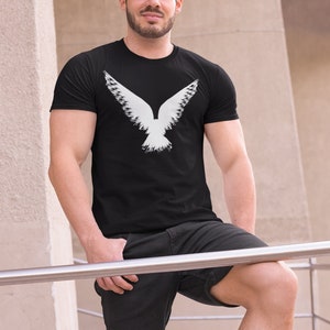 Gothic graphic shirt depicting a Raven design, worn by a witchy male model. Bella Canvas gothic tees are 100% Airlume combed & ringspun cotton made in the USA. Norse apparel with cotton fabric and Viking Raven graphic logo.