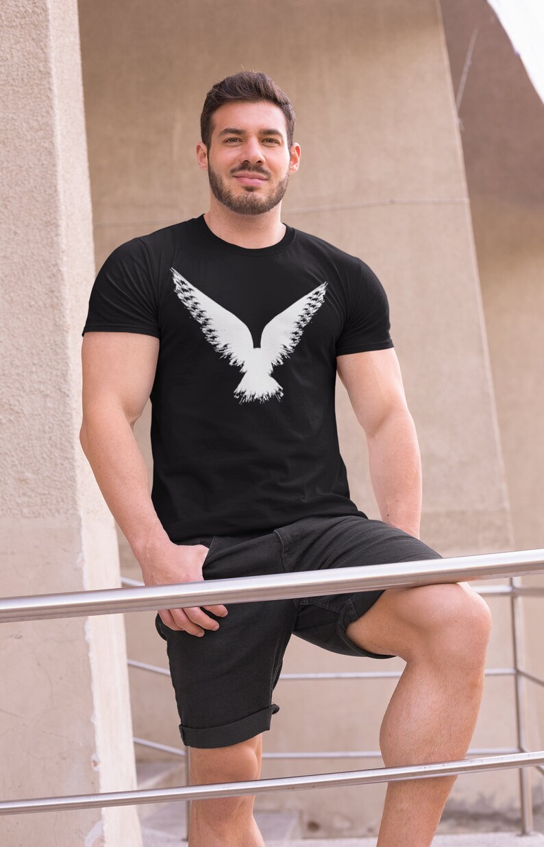 Gothic graphic shirt depicting a Raven design, worn by a witchy male model. Bella Canvas gothic tees are 100% Airlume combed & ringspun cotton made in the USA. Norse apparel with cotton fabric and Viking Raven graphic logo.
