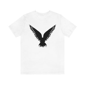 May include: White t-shirt with a black silhouette of a bird in flight.