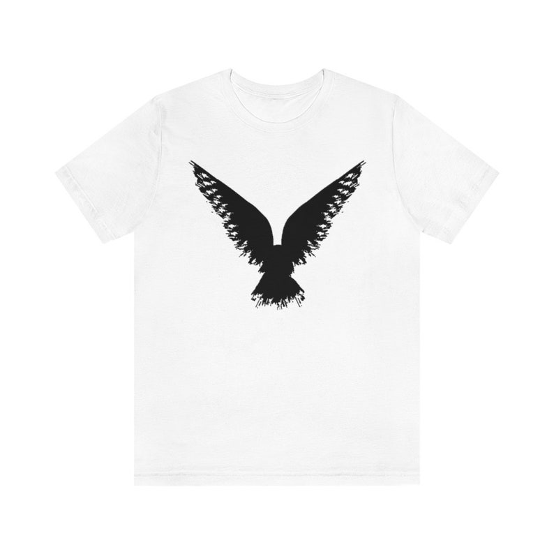 May include: White t-shirt with a black silhouette of a bird in flight.