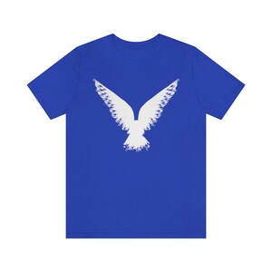May include: A royal blue t-shirt with a white stylized image of a bird with its wings spread.