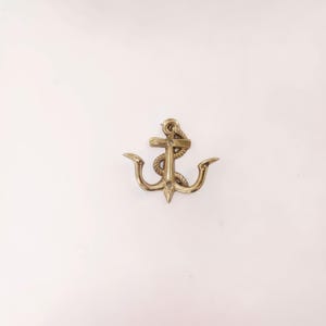 May include: A brass anchor with a rope wrapped around the top. The anchor has curved arms and a pointed bottom. The nautical-themed decor is set against a white background.