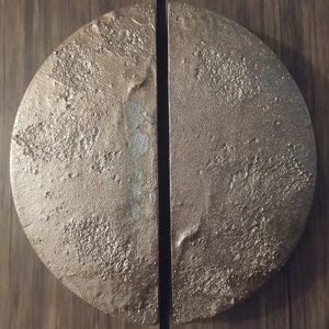 以下が含まれることがあります： 表面がテクスチャ加工された、丸い金色のドアノブのペア。ノブは半分に分割され、木製のドアに取り付けられています。