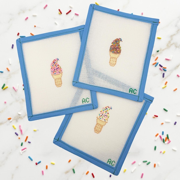 Può includere: Tre tele quadrate per ricamo con bordi in tessuto blu, ognuna caratterizzata da un disegno di cono gelato ricamato con zuccherini colorati. Ogni tela mostra le iniziali AC ricamate in verde nell'angolo inferiore, su una trama a griglia.