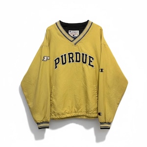 May include: A gold-coloured Purdue University pullover windbreaker with a V-neck and black and gold striped trim. The word "PURDUE" is across the chest in black lettering. The Champion logo is visible on the sleeve.