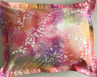 May include: A pink, orange, and purple pillow with a white galaxy print. The pillow has a white border and is made of a soft, comfortable fabric.