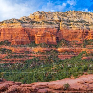 May include: A landscape photograph showcasing a natural rock arch in a desert setting. The image displays a red rock formation with layers of orange and tan colours, vibrant green vegetation, and a blue sky with clouds. The text "DAVID J PARKER Photography" is visible.