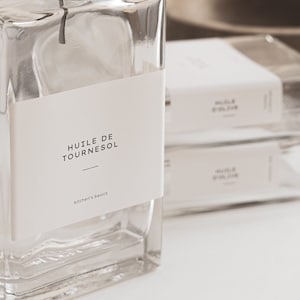 Puede incluir: Una botella de vidrio transparente con un pico de vertido plateado y una etiqueta blanca que dice "HUILE DE TOURNESOL - Kitchen Basics".