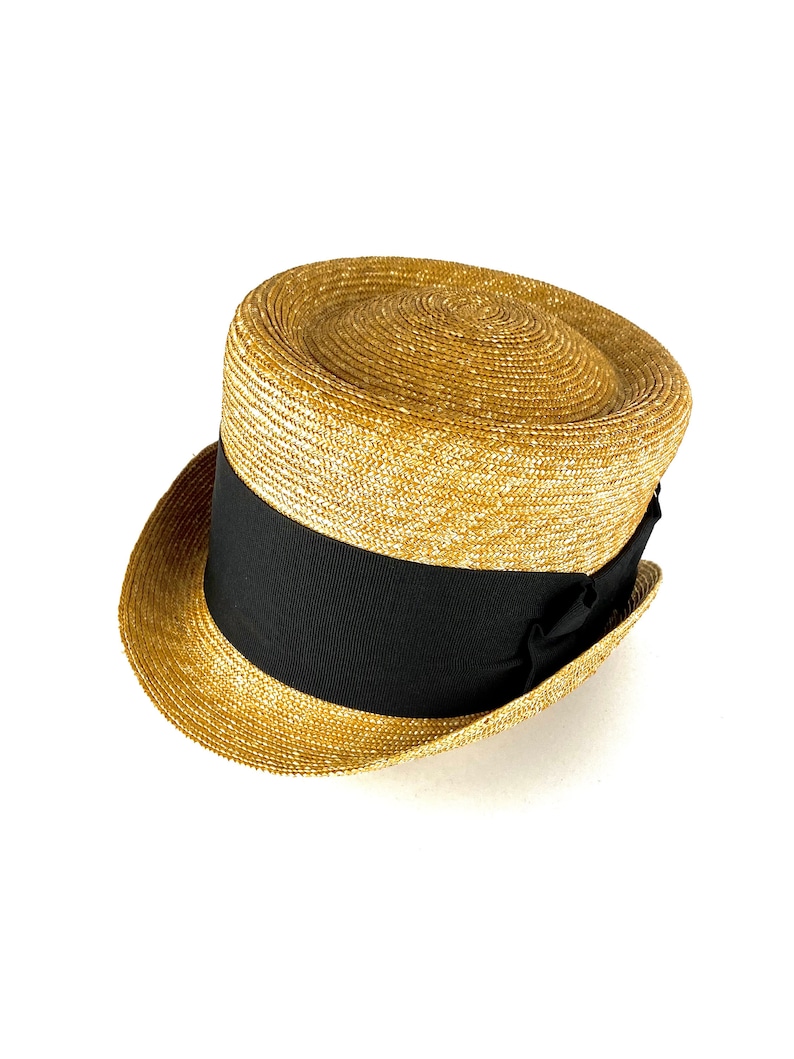 Peut inclure: Un chapeau de paille avec un ruban noir autour de la couronne. Le chapeau est de couleur brun clair et a une forme l&eacute;g&egrave;rement arrondie.