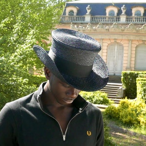 May include: A black top hat with a wide brim and a black band. The hat is made of a woven material and has a slightly textured surface.