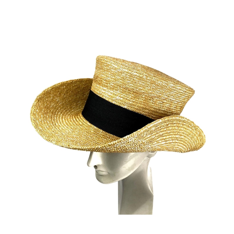 Pu&ograve; includere: Un cappello di paglia a tesa larga con un nastro nero attorno alla corona. Il cappello &egrave; fatto di un materiale di paglia intrecciata e ha una tesa leggermente inclinata.
