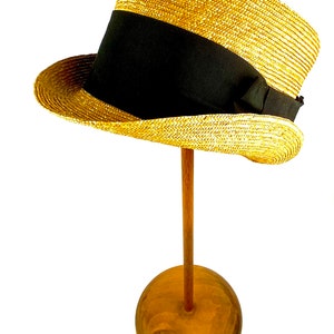 Peut inclure: Un chapeau de paille avec un ruban noir et un n&oelig;ud. Le chapeau est sur un support en bois.