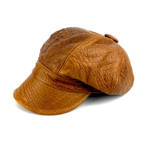 May include: A brown leather newsboy cap with a crocodile-embossed pattern.