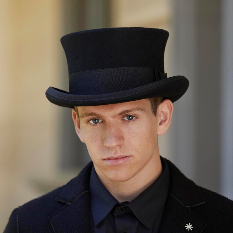 May include: A black top hat with a tall, cylindrical crown and a wide brim. The hat is made of felt and has a black grosgrain ribbon band around the crown.