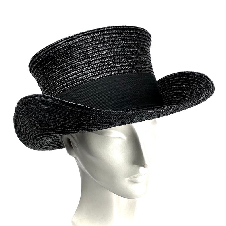 May include: A black straw top hat with a wide brim. The hat has a black ribbon around the crown.