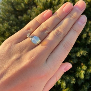 May include: A silver wire wrapped ring with a white opal gemstone.