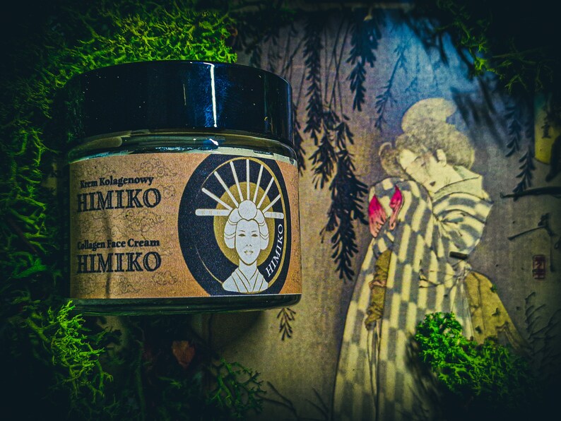 以下が含まれることがあります： 「Krem Kolagenowy HIMIKO Collagen Face Cream HIMIKO」と金色に書かれたラベルが貼られた茶色の瓶。瓶は緑色の苔むした表面に置かれ、その前にヴィンテージの日本の絵画が飾られている。