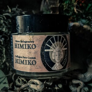 以下が含まれることがあります： 黒い蓋と「Krem Kolagenowy HIMIKO Collagen Face Cream HIMIKO」と書かれたラベルが付いた、小さな丸い顔用クリームの瓶。ラベルには、伝統的な日本の着物姿の女性の絵も描かれている。