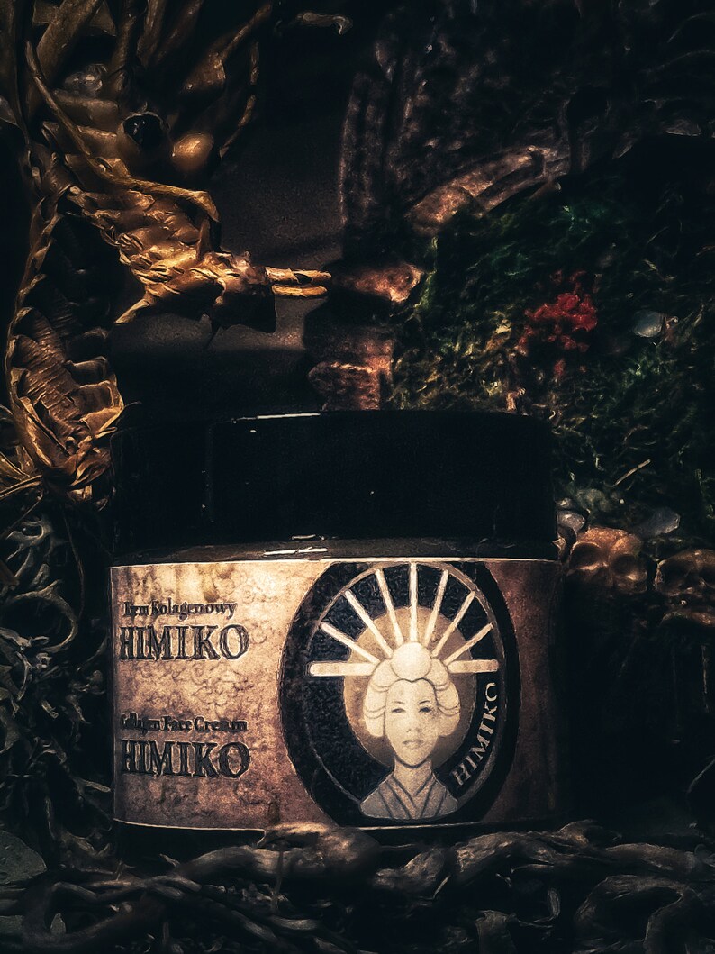 以下が含まれることがあります： 「Irm Kolagenowy HIMIKO Collagen Face Cream HIMIKO」と金色に書かれたラベルが付いた、濃い茶色の瓶。ラベルには、伝統的な日本の着物姿の女性が、日の丸を背負って描かれた白黒のイラストが描かれている。