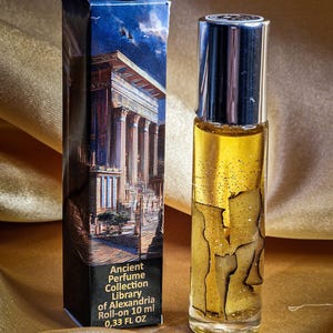 May include: A roll-on perfume bottle and its box. The bottle is clear with a silver cap, filled with a golden liquid and decorative elements. The box features an illustration of an ancient building and text that reads "Ancient Perfume Collection Library of Alexandria Roll-on 10 ml 0.33 FL OZ."