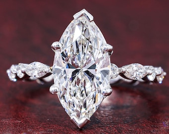 May include: A silver-toned ring featuring a large marquise-cut center stone held by six prongs. The band is adorned with a series of smaller marquise-cut stones set along both sides, creating a continuous sparkling effect across the finger.