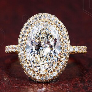 May include: A gold engagement ring with a large oval-shaped diamond surrounded by a double halo of smaller diamonds.