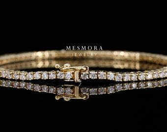 Könnte beinhalten: Ein goldenes Tennisarmband mit einer Reihe kleiner, runder Diamanten. Das Armband hat einen Verschluss.