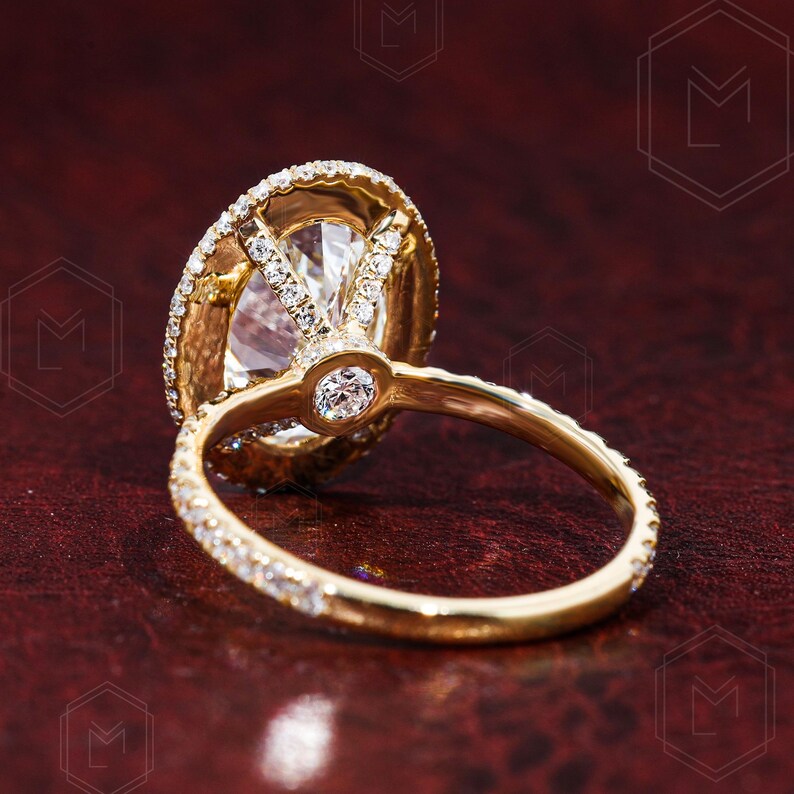 May include: A gold engagement ring with a large oval-shaped diamond surrounded by smaller diamonds. The ring has a delicate band with a row of smaller diamonds.
