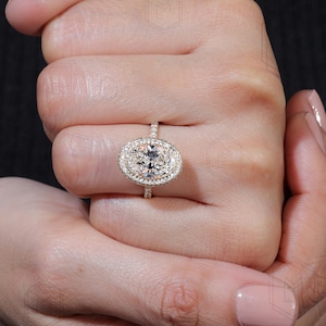 May include: A gold engagement ring with a large oval-shaped diamond surrounded by a double halo of smaller diamonds.